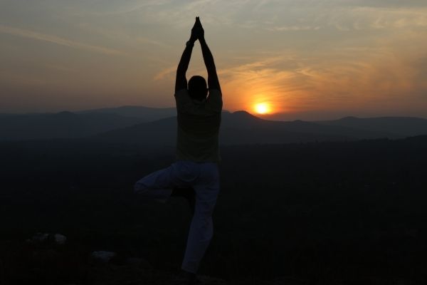 Old man practising Yoga under tree guided by Yoga teacher Online